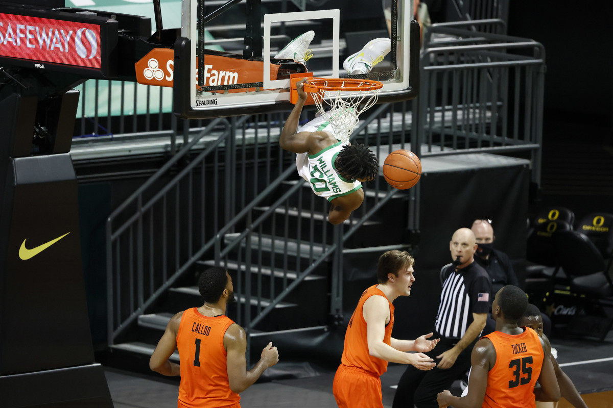 Eric Williams Jr. (50) hangs from the rim after throwing down a dunk against Oregon State on January 23, 2021 at Matthew Knight Arena in Eugene, Oregon.